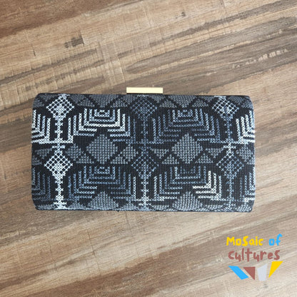 Black and white patterned clutch bag on a wooden surface with 'Mosaic of Cultures' branding.
