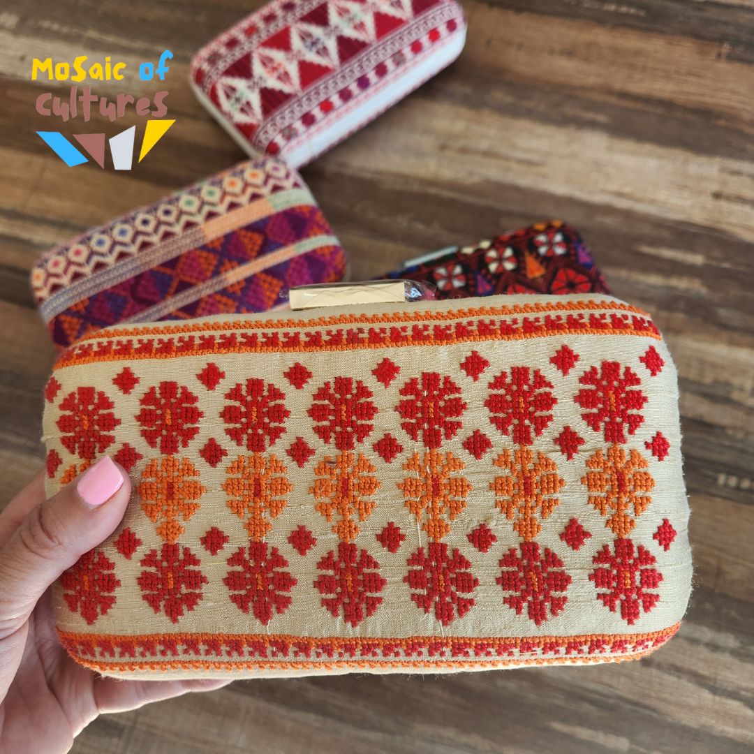 Handheld traditional patterned pouch with 'Mosaic of Cultures' branding on a wooden surface.